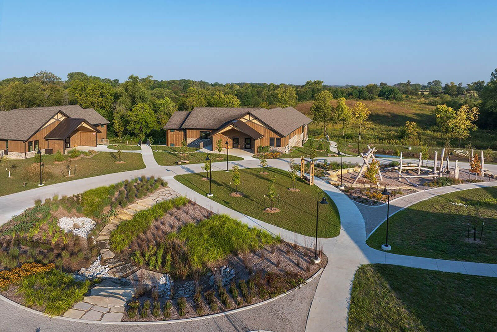 An aerial view of a peaceful residential treatment campus with walking paths, landscaped grounds, and modern buildings surrounded by nature.